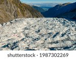 Looking down to the dramatic ice floor of the Southern alps glacier with a red helicopter flying below