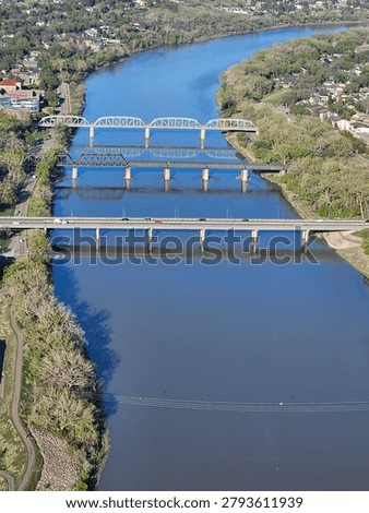 Looking down from an elevated drone point of view at an urban scene of three bridges crossing a water of calm water.