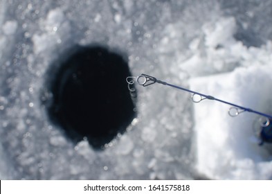 Looking Down The Fishing Line Of The Ice Fishing Pole On The Frozen Lake In The Sunlight.