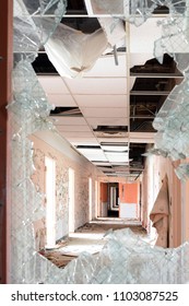 Looking Down Hallway Through Broken Door Window In An Abandoned Hospital Building