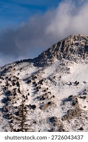 Looking down into a deep valley with snowy slopes and pine forests under a bright blue winter sky showing the immense scale and beauty of the remote high altitude alpine wilderness region area