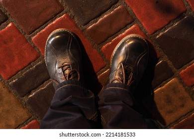 Looking Down Man Feet On Wet Cobbled Road At Night