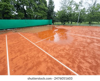 Looking down the nets across the many tennis courts wet after a rain shower 