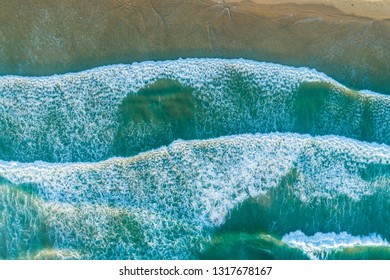 Looking down at ocean waves pound on the shore