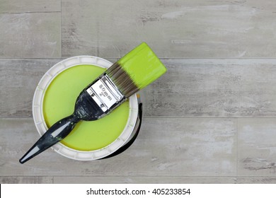 Looking Down On A Can Of Lime Green Paint With A Loaded Brush Stood On A Shabby Style Wood Floor