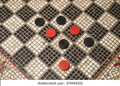 Looking Down On A Checkers Game Board With Red And Black Round Wood Checkers On The Squares.
