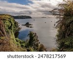 Looking down on the coastline and sea near to Oban on Stewart Island. With the still sea reflecting the sky.