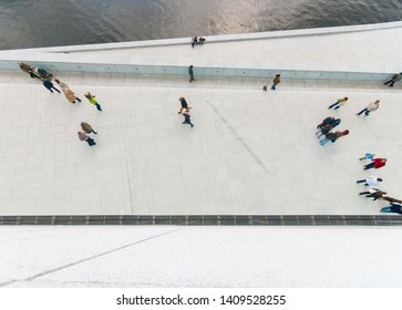 Looking Down On Pepole Walking On A White Concrete Walkway.