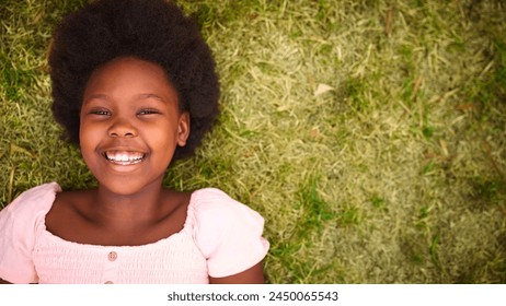 Looking Down On Smiling And Laughing Young Girl Outdoors Lying On Grass In Garden Or Countryside - Powered by Shutterstock