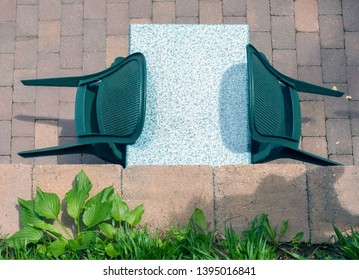 Looking down on a table for two with green flora in the foreground.