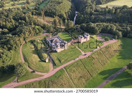 Looking down onto Chatelherault Hunting Lodge, a historic building within Chatelherault Country Park, Scotland. The main house is surrounded by greenery on all sides.