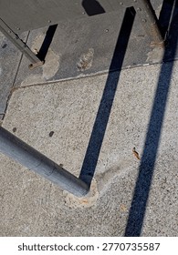 Looking down at sidewalk mounted pole, mailbox with deep shadows