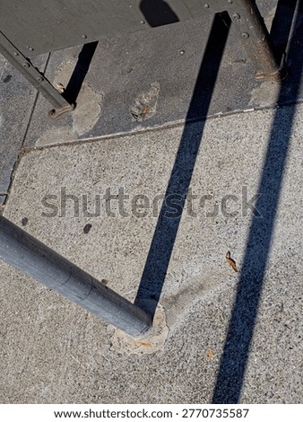 Looking down at sidewalk mounted pole, mailbox with deep shadows
