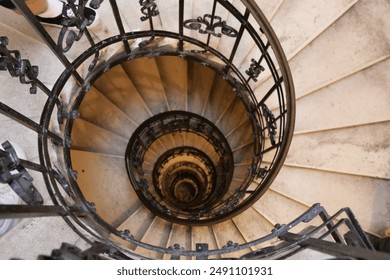 Looking down a spiraling staircase with ornate iron railings, creating a mesmerizing and dizzying visual effect. - Powered by Shutterstock