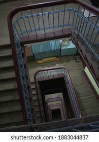 Looking down to stairwell with Spiral staircase with thick wooden railing and residents chest in old Russian Stalin era residential building in day light