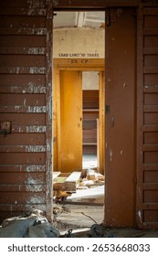 Looking down through two doors in an old, abandoned railway carriage, one door faded red, one yellow, with an old text sign 
