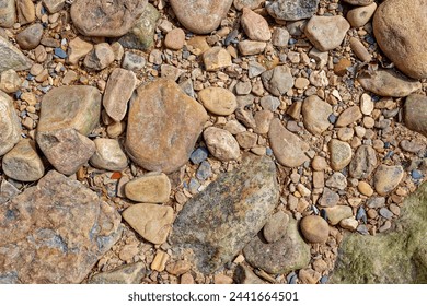 Looking down at a variety and sizes of colorful rocks on the shoreline along the river closeup view for backgrounds and textures copyspace and wallpaper - Powered by Shutterstock