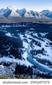 Looking down view winter river flowing through snow covered mountains in Banff National Park taken from Tunnel Mountain.