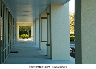 Looking Down Walkway In Front Of Generic Florida Strip Mall With Shop Doors On The Left And Columns On The Right.