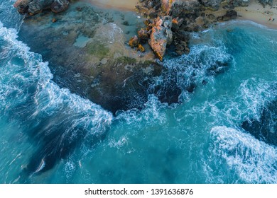 Looking down at waves crushing over rocks - aerial view