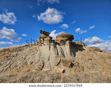 Looking up at dry and arid hoodoo rock formations with brown grass and blue sky