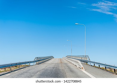 Looking up an empty, grey bridge.