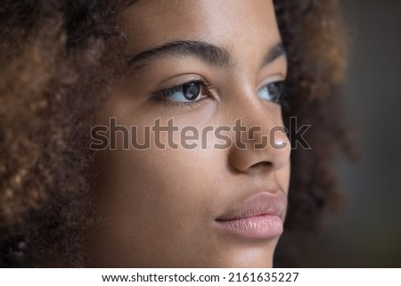 Looking forward. Close up face teen Afro American lady staring far away. Brown eyes of serious young woman wearing modern soft contact lenses. Female patient enjoy good eyesight after laser correction