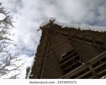 Looking up to Gassho-zukuri traditional japanese thatched roof house with big snowdrifts
