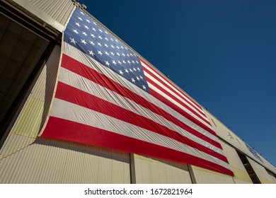 Looking Up At A Giant  American Flag On The Side Of A Hangar Building