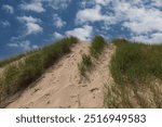 Looking up a grassy sand dune in Kohler Andrae State park, in Sheboygan, Wisconsin, on a summer day