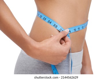 Looking great. Studio shot of a woman measuring her waistline.