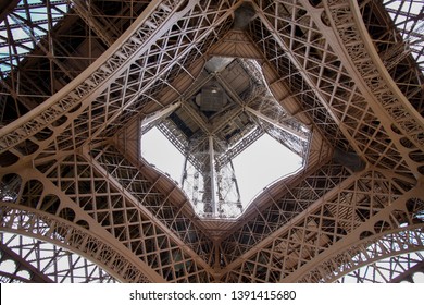 Looking up the iconic Eiffel Tower from the base on a spring summer day with blown out sky. Tourists consider Paris as the world's most romantic city and Eiffel tower most visited place 