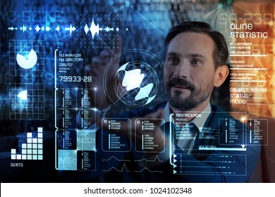 Looking impressed. Smart emotional programmer standing next to a futuristic transparent screen and feeling impressed by it