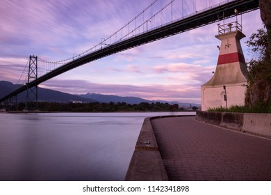 Looking Into The Bay With The Lions Gate Bridge Going Over Top And A Lighthouse In The Front