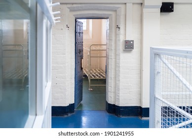 Looking into prison cell block victorian British English jail house with bed in room lock up high security room derelict old new category A B C in custody with bars door open confined escaping