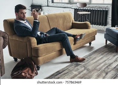 Looking into your heart. Handsome young man in full suit holding eyewear and looking at camera while sitting on the sofa - Shutterstock ID 757863469