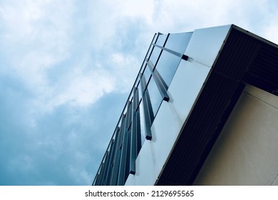 Looking Up At A Mid Century Building And It’s Sharp Roof Line Against A Cloudy Blue Sky