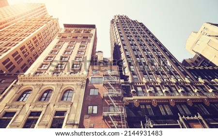 Looking up at old Manhattan buildings against the sun, color toned picture, New York City, USA.