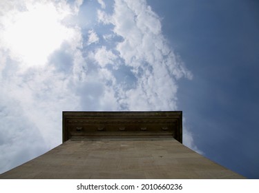 Looking up at one of the pillars of Széchenyi Chain Bridge in Budapest Hungary, with blue sky and white clouds and sunshine in the background
