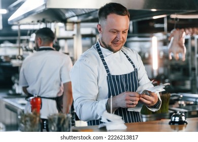 Looking at orders and checks. Kitchen workers is together preparing the food. - Powered by Shutterstock