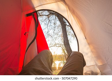 Looking out from interior of tent sunrise. Adventure traveling in Africa National Parks. Outdoor activities. Human legs, open door.
