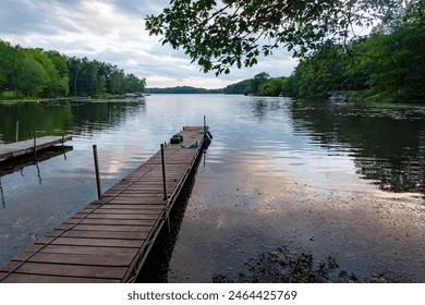 Looking out onto a Wisconsin lake  while  the last rays of sunlight play in the  clouds and are reflected in it's calm surface.  Various boat docks dot the shore. - Powered by Shutterstock