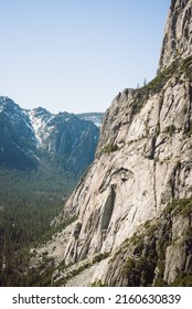 Looking out over the cliffs of the mountains in Yosemite from the Yosemite falls trail. Giant trees in the foreground and massive rock walls of the cliffs rise up in the background. Yosemite Falls. - Shutterstock ID 2160630839