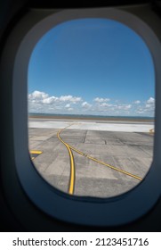 Looking Out Over the Tarmac from Airplane Window Towards the Ocean in Auckland New Zealand On Bright Summers Day