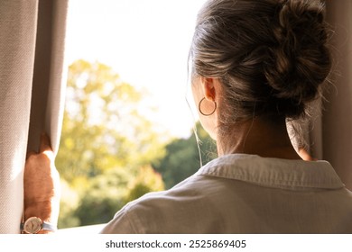 Looking out window, senior woman with bun hairstyle enjoying peaceful morning at home, copy space. Lifestyle, relaxation, indoors, tranquility, serenity, calm - Powered by Shutterstock