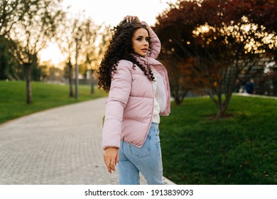 Looking Over The Shoulder Of Someone Looking In The Park Is A Beautiful Girl In A Warm Jacket And Jeans. High Quality Photo