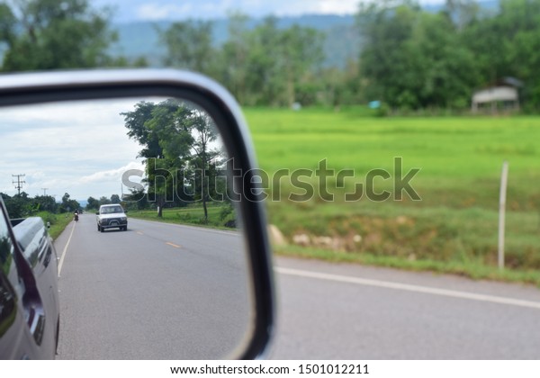 Looking at the rear\
mirror when driving a car.9/9/2019.Chat Trakan District /\
Phitsanulok - Thailand\
Province