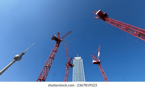 Looking up at the red tower cranes and the TV Tower at a construction site of a high-rise building in Berlin, Germany - Powered by Shutterstock