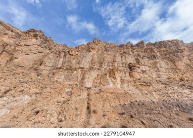 Looking up at a rocky cliff face with blue sky in rural New Mexio - Powered by Shutterstock