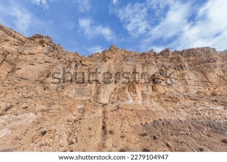 Looking up at a rocky cliff face with blue sky in rural New Mexio
